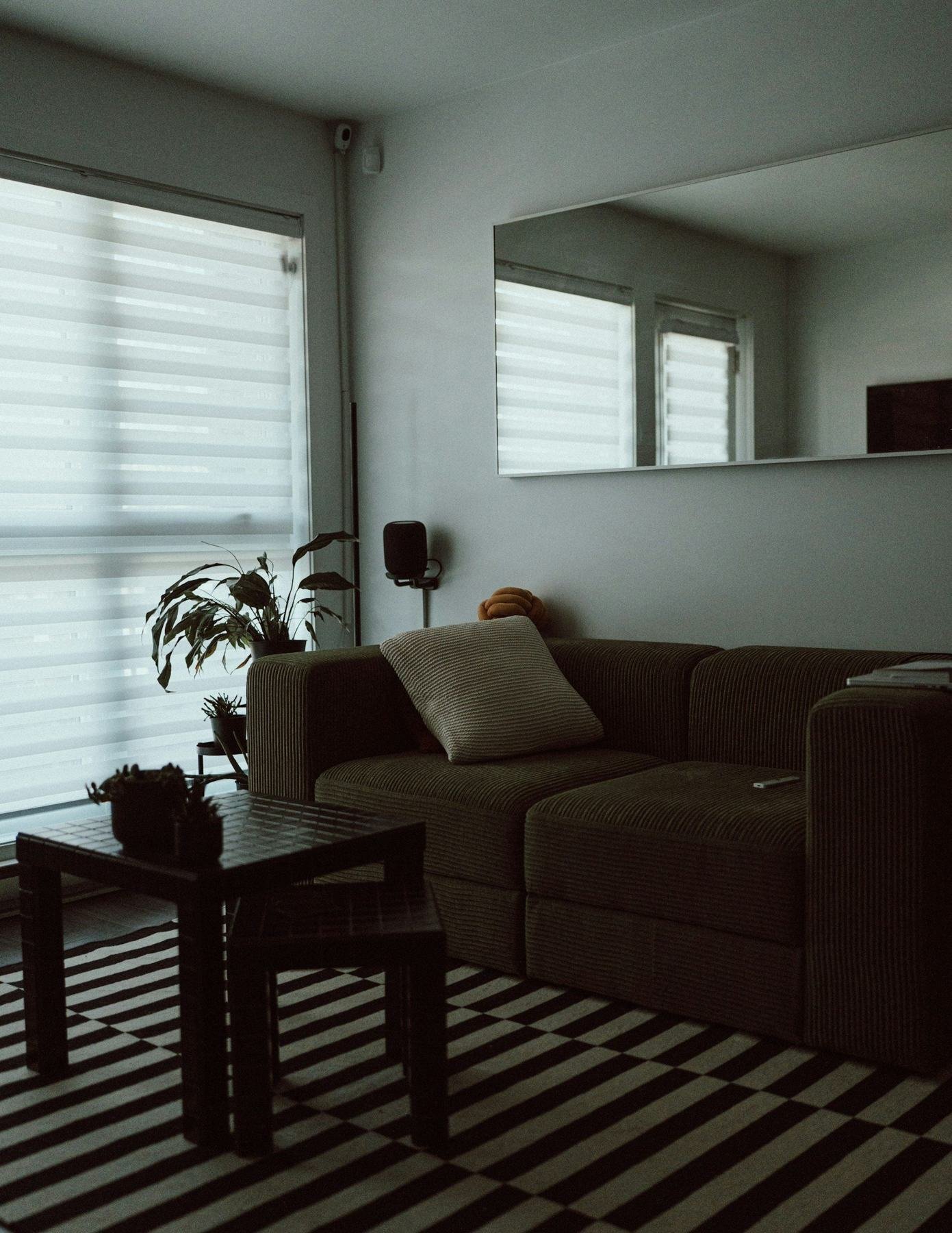 A brown sofa and wooden coffee table in a softly lit room with window blinds.