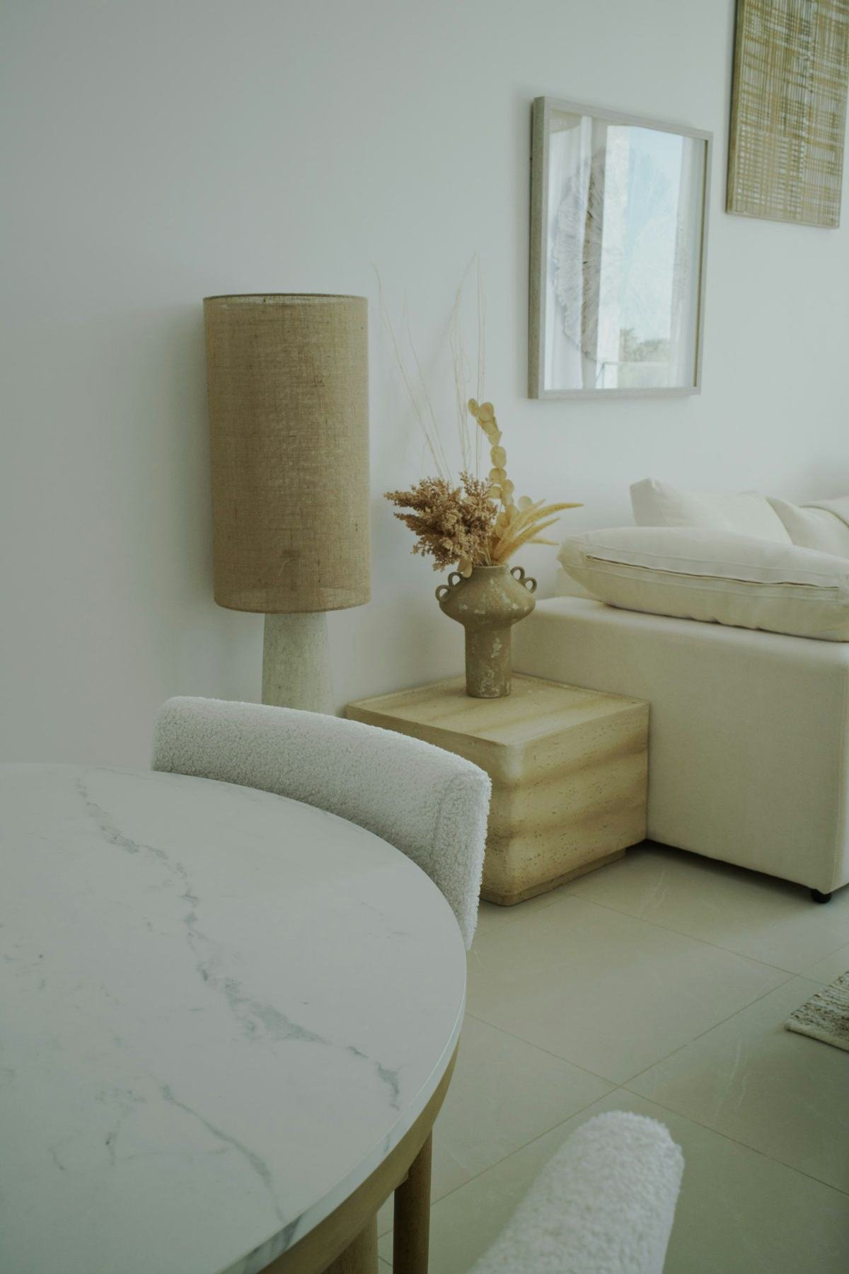 Neutral seating, a wooden side table and framed art beside a cream wall.